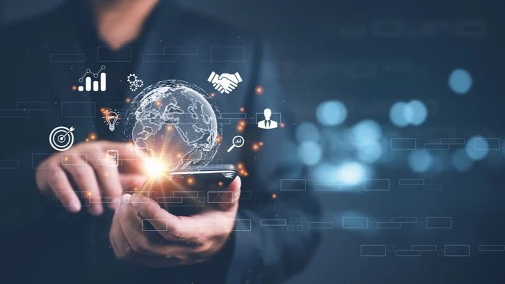 A hand holding a phone with a digital globe and business icons above it